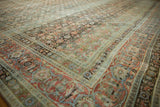 Distressed vintage Tabriz rug detail with worn dusty teal and terra cotta Herati motifs.