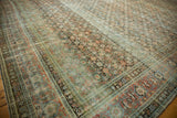 Traditional Persian Tabriz carpet showing distressed Herati motifs in dusty teal and terra cotta.