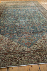 Distressed Malayer carpet corner showing Herati motif, meandering vine border, dusty blue and ivory tones.