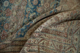Folded distressed Malayer carpet revealing dusty sky blue Herati motifs and meandering vine border.