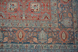Close-up of a vintage Bijar carpet corner showing distressed floral patterns in red and blue.