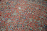 Angled view of the distressed pile on a vintage Bijar with ruby and blue floral motifs.