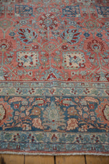 A crease runs between the floral border and ruby red field of a distressed vintage Bijar carpet.