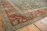 Worn rust border and deep green floral field of a vintage distressed Sarouk rug corner.
