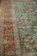 Distressed vintage Sarouk rug: faded floral patterns in deep green field and rust border.