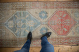 Distressed vintage Persian runner featuring a field of muted blue and coral geometric medallions.