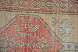 Distressed vintage Northwest Persian runner: geometric pattern, faded red, beige, teal, visible foundation.