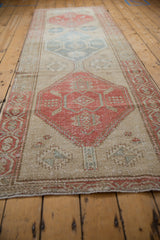 Distressed vintage Northwest Persian runner, close-up of worn beige field with pale teal motifs.