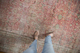 Softly worn texture on an antique Kermanshah carpet with scrolling floral patterns in dusty red and ivory.