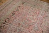 Angled corner view of a distressed Kermanshah carpet's intricate floral field and multi-layered border.