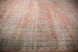Scrolling arabesques and floral motifs in the time-softened border of a Persian carpet.
