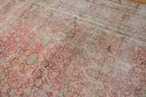 Mostly even, time-softened wear over the red and ivory florals of a distressed Kermanshah carpet.
