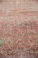 Worn, low pile detail on a distressed Kermanshah carpet with scrolling red and ivory floral motifs.