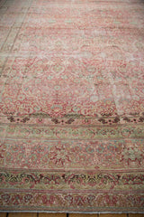 Time-softened red and ivory tones across the floral borders of a distressed antique Persian carpet.