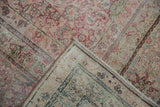 Folded corner of a distressed Kermanshah carpet revealing the worn, low pile and intricate border.
