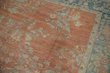 Distressed vintage Mahal carpet detail showing pale terra cotta field, faded floral sprays, and worn blue border.