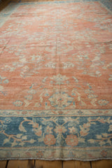 Close-up of distressed Mahal rug with coral field floral sprays and blue meandering vine border.