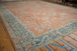 Corner of Distressed Mahal carpet with pale ruby grapefruit field, subtle floral sprays, and blue vine border.
