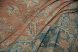 Folded distressed Mahal rug showing floral sprays, pale terra cotta and dusty blue hues.