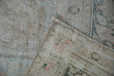 Vintage distressed Doroksh carpet's worn pile revealing foundation, soft ivory and dusty teal.