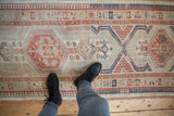 Distressed vintage Serab runner with geometric medallions and abrashes in ivory, terra cotta, blue.