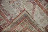 Distressed vintage Serab rug's folded corner showing worn geometric patterns and side selvage.
