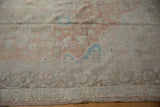 Textured detail of a distressed Oushak rug, showcasing faded copper, ivory, and soft blue patterns.
