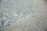 Distressed Heriz carpet detail, powder blue and ivory geometric floral pattern with faint foundation showing.