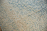 Distressed pile of vintage Heriz rug, with powder blue and ivory floral-geometric patterns.