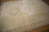 Distressed Oushak carpet featuring geometric borders and subtle abrashes in beige and ivory.