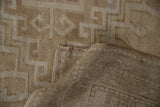 Distressed pile and hooked geometric motifs with neutral abrashes on a vintage Oushak carpet.