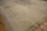 Distressed beige Oushak rug's narrow border featuring geometric palmette motifs.