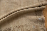 Distressed Oushak rug's folded beige pile with geometric palmette border motifs.