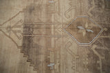 Distressed vintage Oushak rug: abrashed geometric motifs, floral cross-section, beige and brown tones.