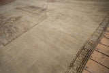 Distressed vintage Oushak rug section: abrashed geometric vines, floral motifs, and palmette border.