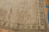 Vintage distressed Oushak rug corner, abrashed beige field, geometric palmette border motifs.