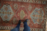 Distressed Hamadan rug's chestnut, dusty blue geometric floral bouquets, pinwheels, and textured wear.
