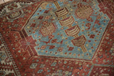 Distressed vintage Hamadan rug: worn blue field with geometric floral buds and red border.
