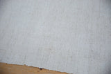 Hand-woven flatweave texture with subtle ivory specks and natural rough edge.