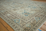 Distressed corner of the Sparta carpet with ivory, denim blue, and brown geometric motifs.