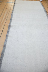Perspective view of the vintage Turkish runner's speckled ivory flatweave and charcoal selvage.