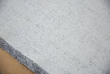 Detail of the hand-spun flatweave's speckled texture and intact charcoal side selvage.
