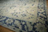 Low angle view of the distressed Oushak carpet's texture and navy geometric border.
