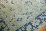 Distressed vintage Oushak pile showing even wear with geometric palmettes in navy and sea foam green.