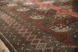 Distressed Ersari carpet detail with dusty wine red guls and geometric borders, even wear.