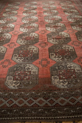 Distressed Ersari carpet showing repeating floral guls and geometric patterns in chestnut and wine red.