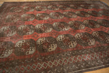 Distressed Ersari carpet corner border detail with geometric diamond pattern in dusty chestnut and ivory.