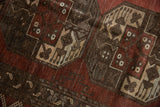 Close-up of vintage Ersari carpet pile, distressed geometric medallions in dusty red and ivory.