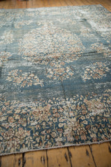Distressed vintage Sparta carpet with faded denim blue, ivory florals, and foundation showing.