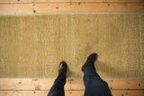 Distressed saffron yellow Khotan runner, showing repeating floral panel motifs and subtle wear.